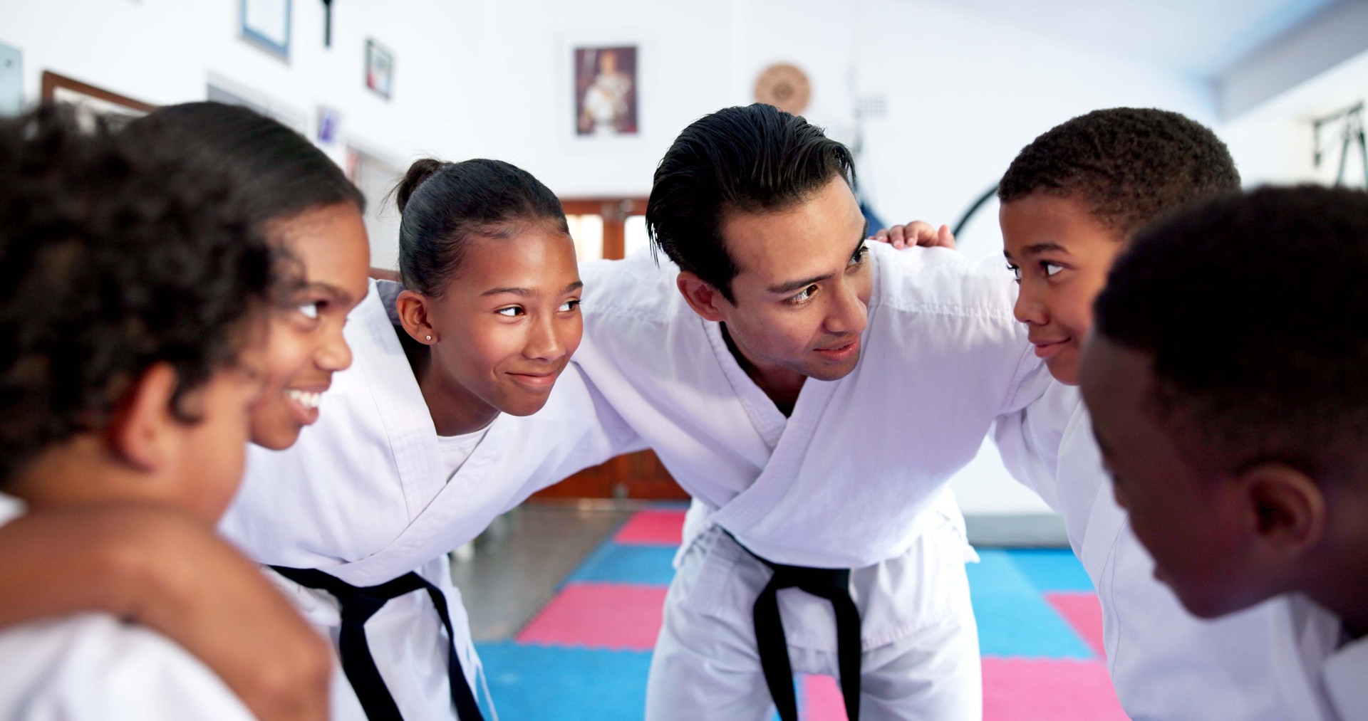 Children, teacher and huddle together in dojo for martial arts training, self defense or fighting competition. Kids, motivation and planning with support for taekwondo challenge or community karate