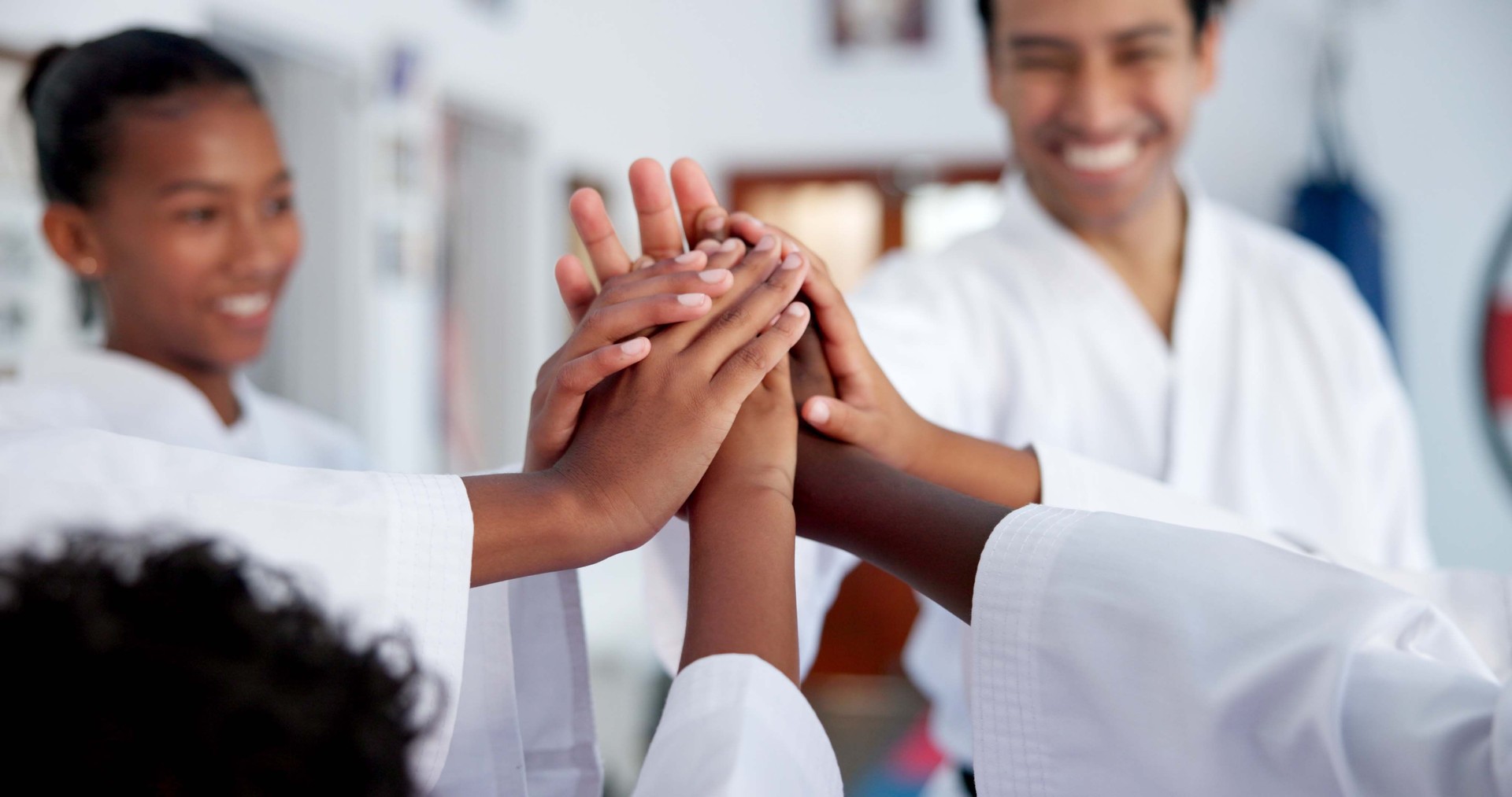 Kids, teacher and hands together in dojo for martial arts training, self defense or fighting competition. Children, motivation and celebration with support for taekwondo challenge or community karate